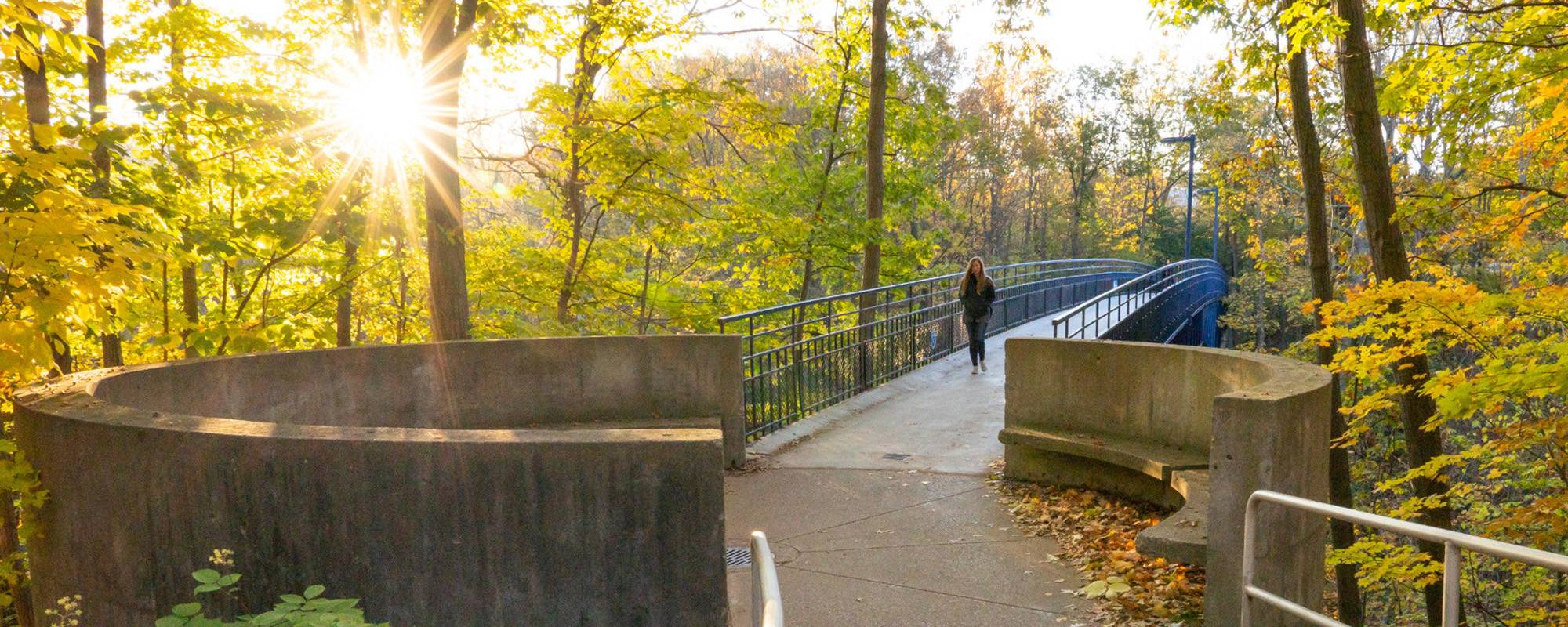 Student finding her way across the Little Mac Bridge on Grand Valley campus.
